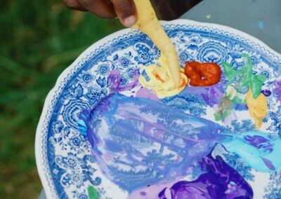 Kind mischt Farben auf einer Palette für sein Naturbild beim Ferienprogramm