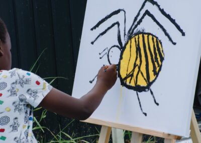 Kind malt eine Wespenspinne auf eine große Leinwand beim Ackerperlen-Ferienprogramm